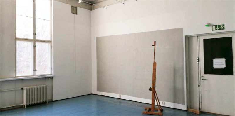 A painting easel in a studio with light walls and high ceiling