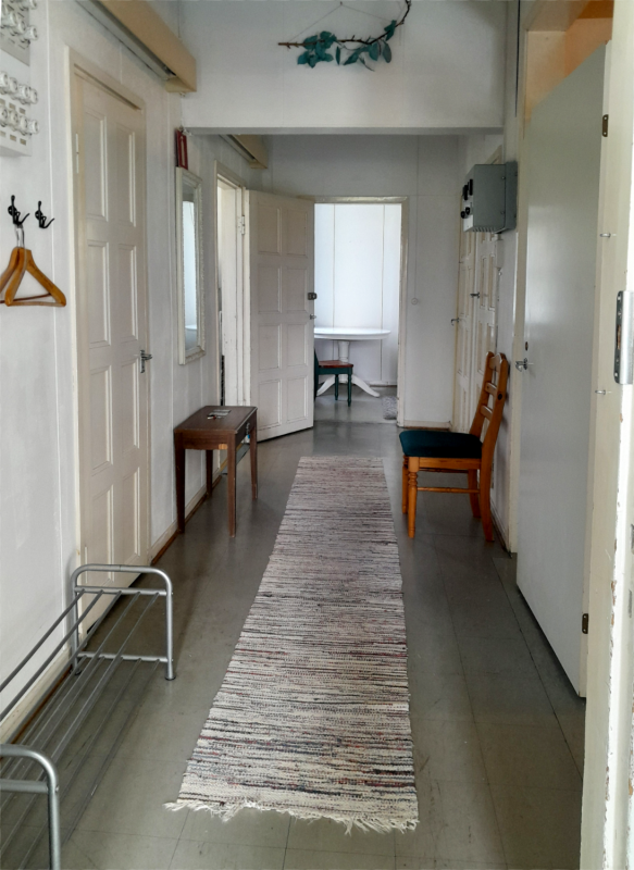 A hallway with a rug, small table and a chair